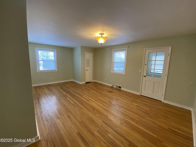 interior space with wood-type flooring, visible vents, and baseboards