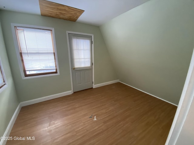 spare room with vaulted ceiling, wood finished floors, and baseboards