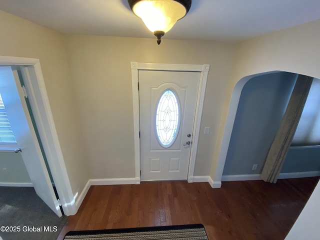 foyer with baseboards, arched walkways, and wood finished floors