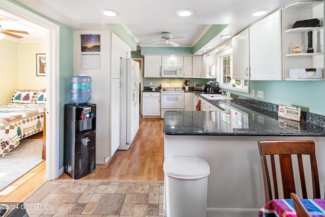 kitchen featuring light hardwood / wood-style floors, kitchen peninsula, white cabinets, and white appliances