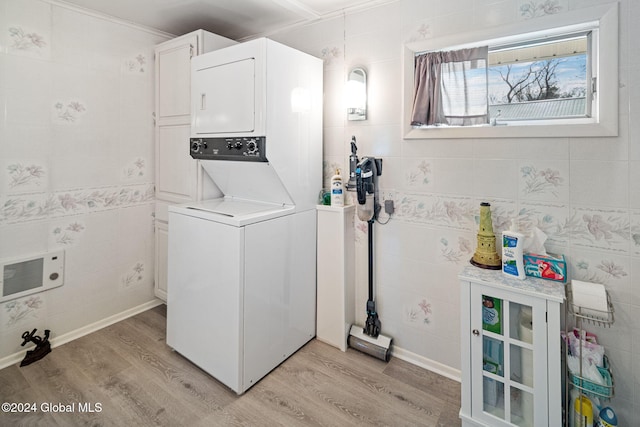 washroom with tile walls, light hardwood / wood-style flooring, stacked washer and clothes dryer, and cabinets