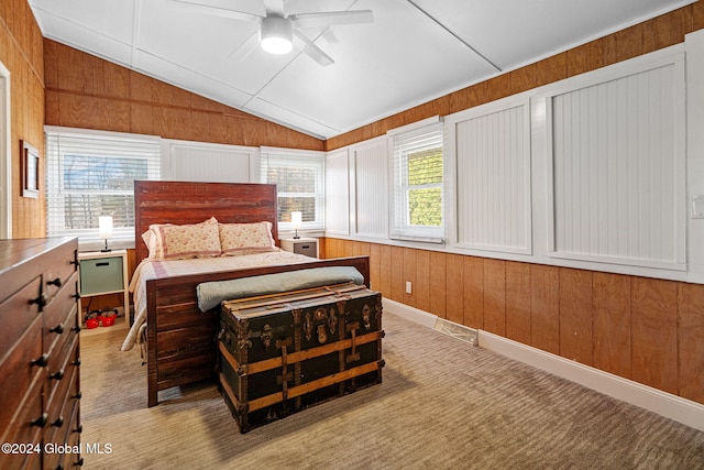 carpeted bedroom featuring multiple windows, wood walls, lofted ceiling, and ceiling fan