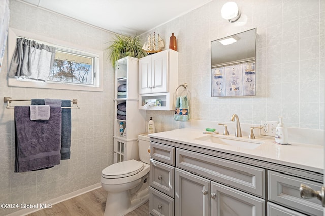 bathroom with toilet, vanity, wood-type flooring, and tile walls