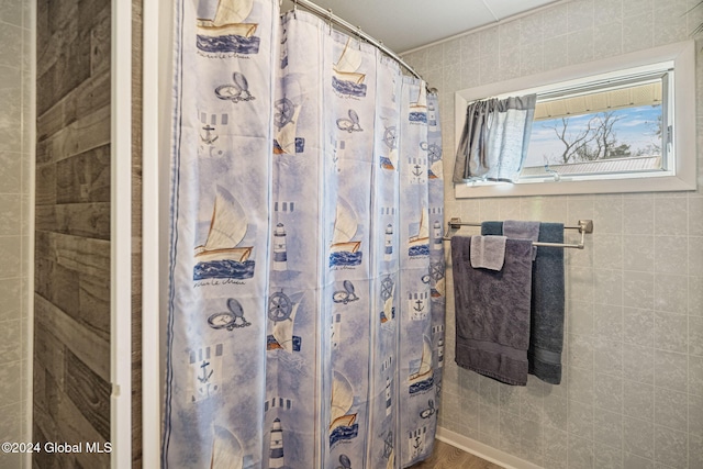 bathroom with tile walls and a shower with shower curtain