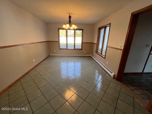 empty room with a baseboard heating unit, a chandelier, and tile patterned flooring