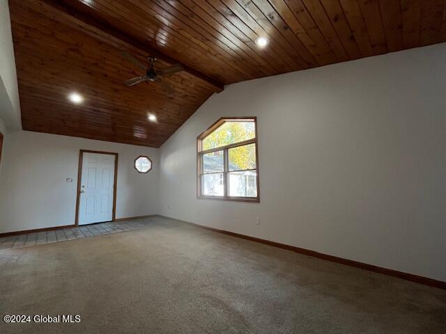 carpeted spare room featuring ceiling fan, wooden ceiling, and vaulted ceiling