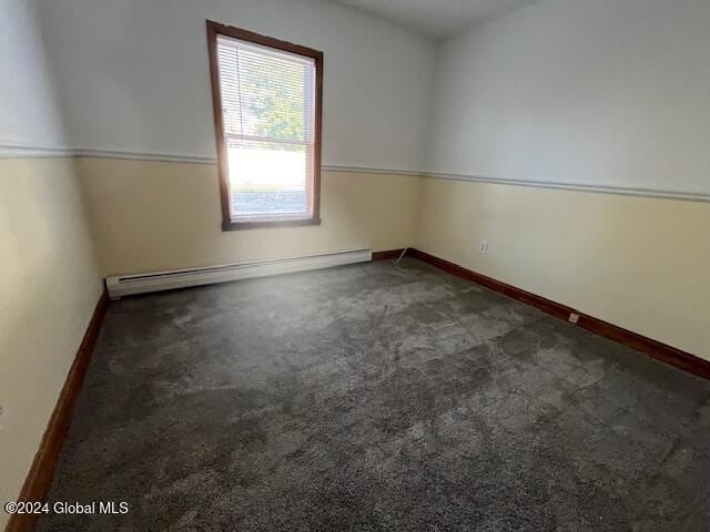 carpeted spare room featuring a baseboard heating unit