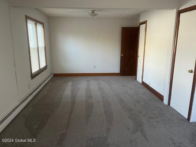 carpeted empty room with a textured ceiling and baseboard heating