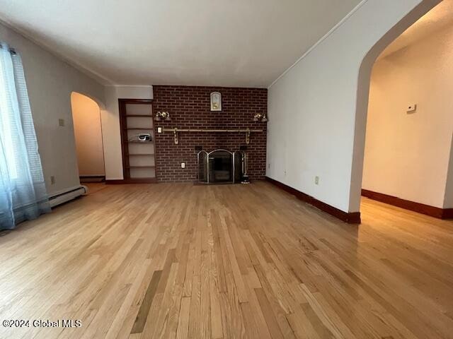 unfurnished living room featuring ornamental molding, a fireplace, and light hardwood / wood-style floors