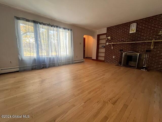 unfurnished living room featuring light hardwood / wood-style floors, a baseboard heating unit, and a brick fireplace