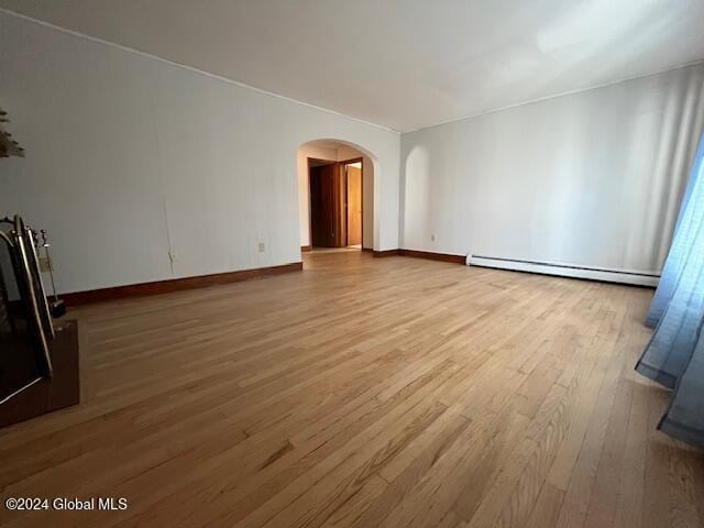 unfurnished living room featuring hardwood / wood-style flooring and a baseboard heating unit