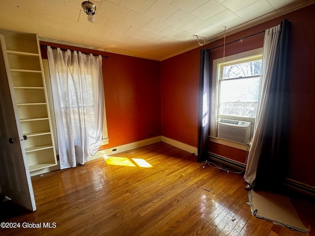 empty room featuring ornamental molding, cooling unit, and hardwood / wood-style flooring