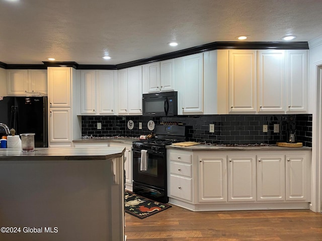 kitchen with light hardwood / wood-style floors, black appliances, and white cabinets