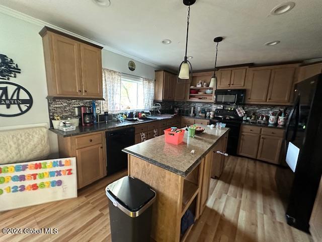 kitchen featuring tasteful backsplash, black appliances, a center island, light hardwood / wood-style floors, and crown molding