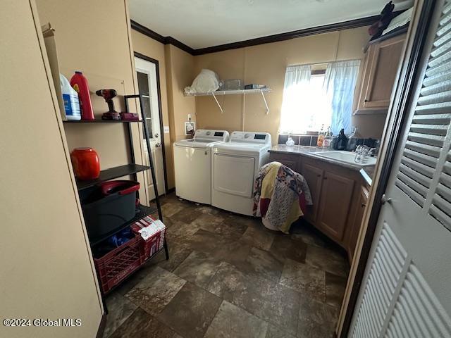 washroom with cabinets, ornamental molding, sink, and washing machine and clothes dryer