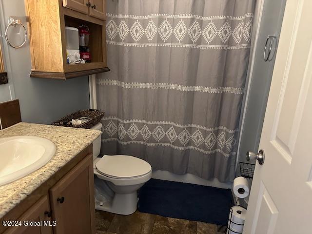 bathroom featuring toilet, vanity, and a shower with shower curtain