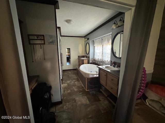 bathroom with vanity, ornamental molding, and a bathing tub