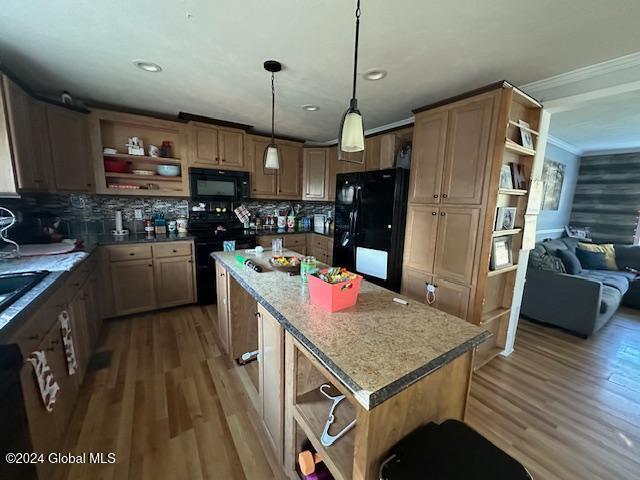 kitchen with dark hardwood / wood-style flooring, a kitchen island, black appliances, crown molding, and decorative light fixtures