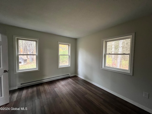 spare room featuring baseboard heating and dark wood-type flooring