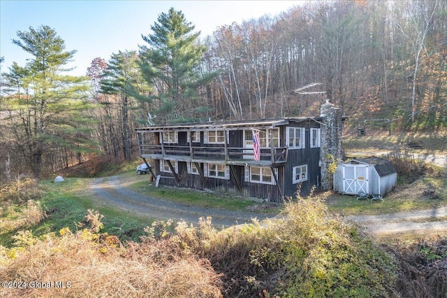 back of property with a wooden deck and a storage shed