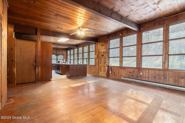 unfurnished room featuring baseboard heating, wood walls, ceiling fan, and light wood-type flooring