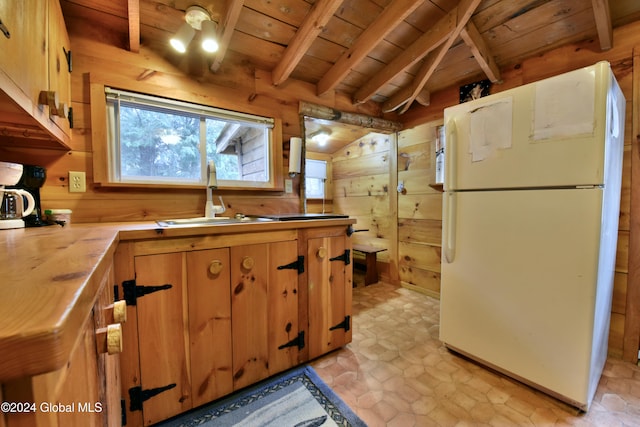 kitchen with wood walls, sink, wooden ceiling, and white refrigerator