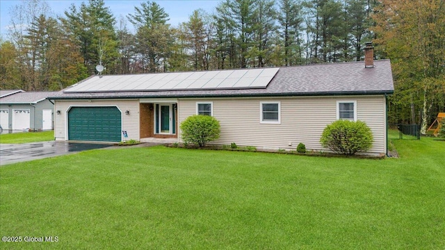 single story home with a garage, asphalt driveway, a front yard, a chimney, and roof mounted solar panels