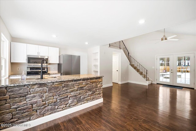 kitchen with appliances with stainless steel finishes, dark hardwood / wood-style floors, light stone countertops, and white cabinets