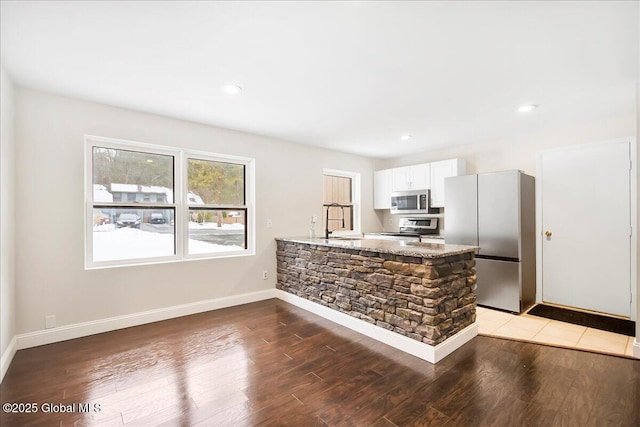 kitchen with sink, hardwood / wood-style flooring, appliances with stainless steel finishes, white cabinets, and kitchen peninsula