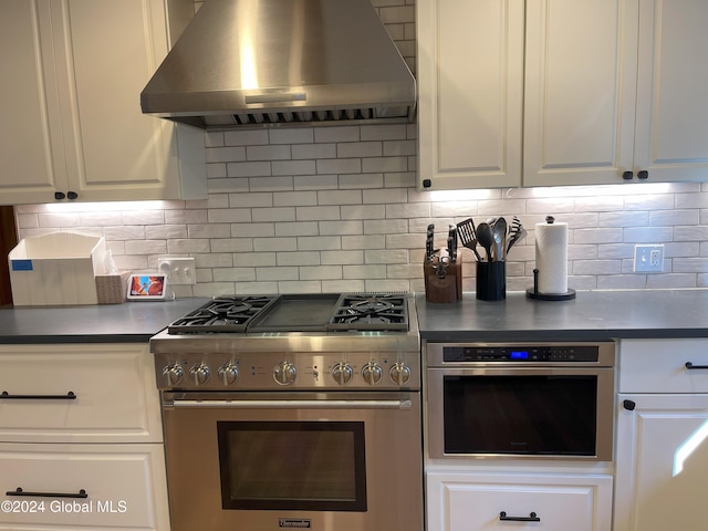 kitchen featuring appliances with stainless steel finishes, wall chimney exhaust hood, white cabinets, and decorative backsplash