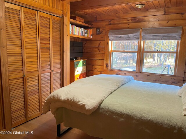 bedroom featuring a closet, hardwood / wood-style flooring, and wooden ceiling