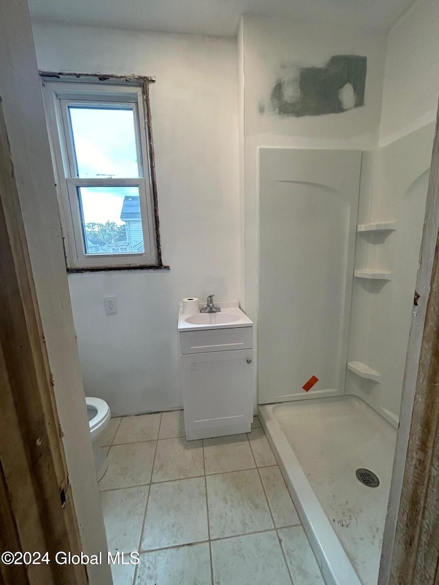 bathroom featuring tile patterned flooring, vanity, toilet, and walk in shower