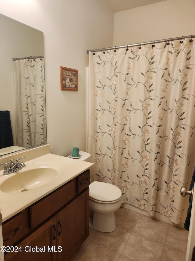 bathroom with toilet, vanity, and tile patterned floors