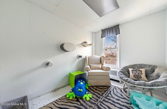 sitting room featuring wood walls and radiator heating unit