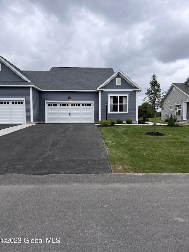 ranch-style house with board and batten siding, an attached garage, driveway, and a front yard
