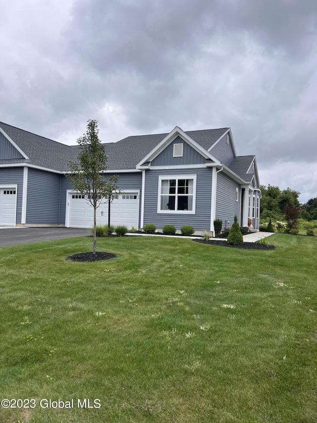 single story home featuring roof with shingles, an attached garage, aphalt driveway, board and batten siding, and a front yard