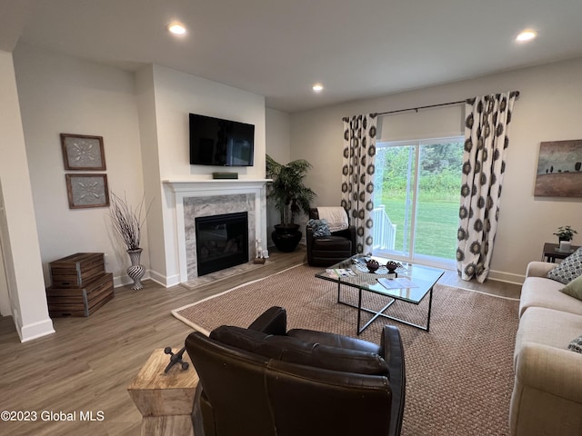 living room featuring a premium fireplace, recessed lighting, and wood finished floors