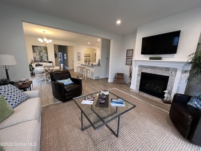 living room with wood finished floors, a fireplace, baseboards, recessed lighting, and a chandelier