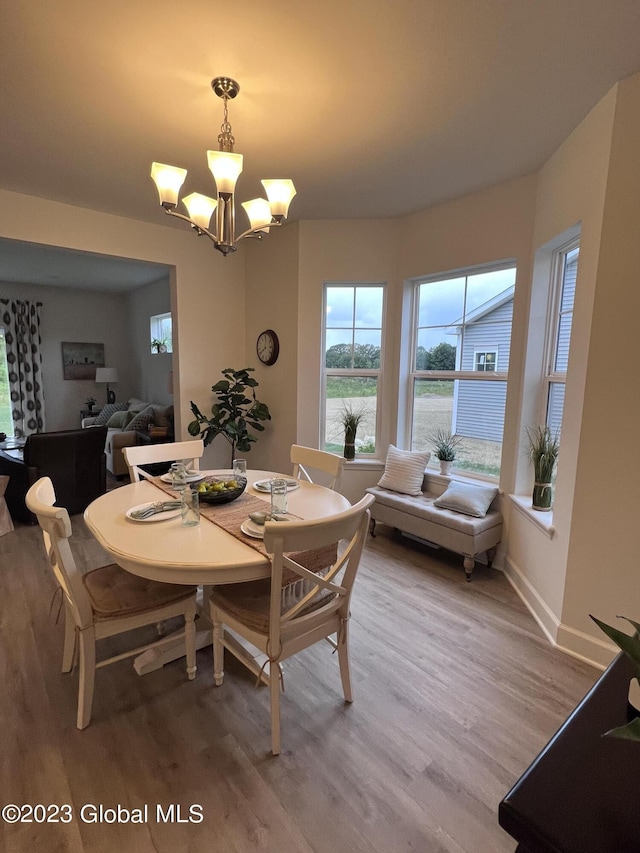 dining area with baseboards, a notable chandelier, and light wood-style floors