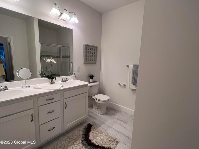 bathroom featuring toilet, vanity, and a shower with door