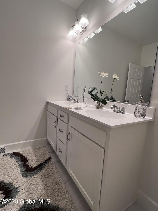 bathroom featuring double vanity, baseboards, and a sink
