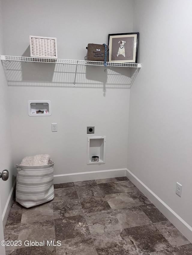clothes washing area featuring laundry area, hookup for a washing machine, electric dryer hookup, stone finish flooring, and baseboards