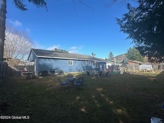 rear view of house with a playground and a yard