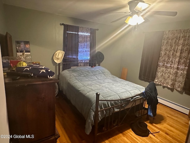 bedroom featuring ceiling fan, wood-type flooring, and a baseboard heating unit