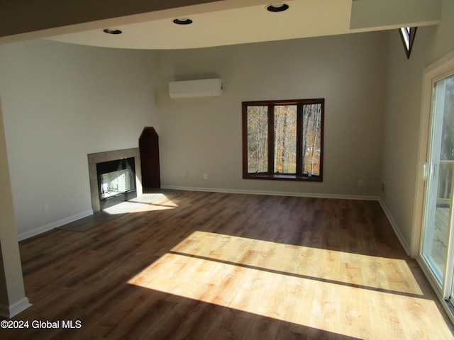 unfurnished living room with dark hardwood / wood-style floors, a tiled fireplace, and a wall mounted air conditioner