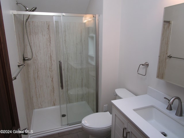 bathroom with toilet, vanity, tile patterned floors, and a shower with shower door