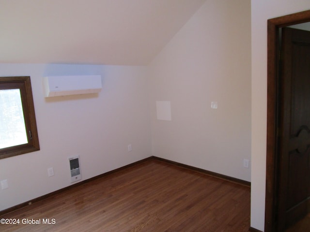 additional living space featuring dark wood-type flooring, a wall mounted AC, and vaulted ceiling