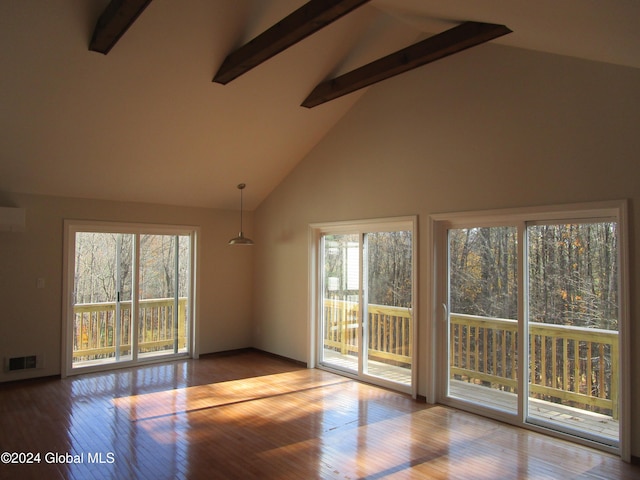 unfurnished living room featuring plenty of natural light, wood-type flooring, and beamed ceiling