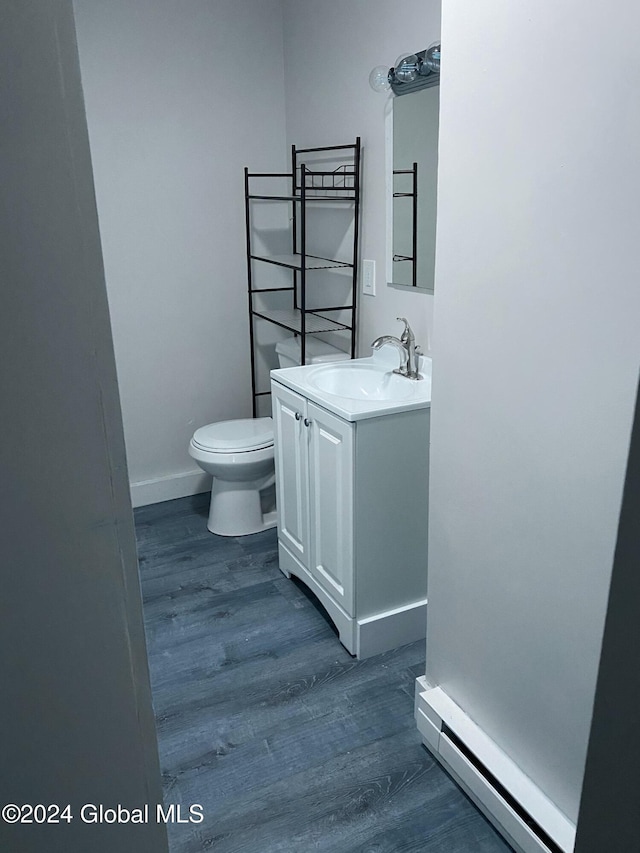 bathroom featuring baseboard heating, vanity, hardwood / wood-style flooring, and toilet