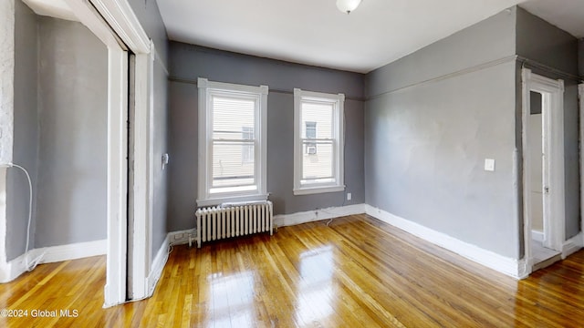 unfurnished bedroom featuring radiator heating unit and wood-type flooring